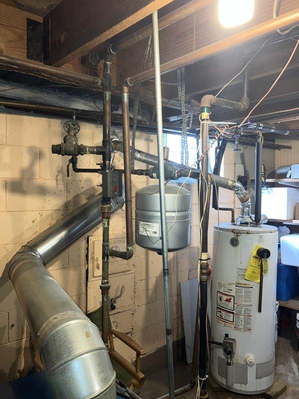 Provided estimate for replacement of non-operational 16-year-old natural gas boiler located in basement. Assessed existing hydronic heating system including circulation pump, zone valves, expansion tank, and interconnected copper and black iron piping network. Documented current equipment configuration and mechanical room layout to prepare comprehensive replacement proposal for new boiler system.