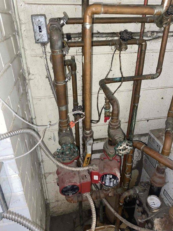 Conducted comprehensive assessment of existing boiler system for replacement estimate. Upon inspection, found aging hydronic heating system with deteriorated copper piping showing significant oxidation and patina, malfunctioning pressure gauge, and circulation pump requiring replacement. Evaluated complex multi-zone plumbing assembly with various gate valves and connections throughout the system. Documented condition of all components including corroded piping, outdated circulation equipment, and electrical connections to provide accurate replacement specifications for new boiler unit installation.