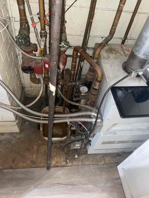 Conducted comprehensive assessment of existing boiler system for replacement estimate. Upon inspection, found aging hydronic heating system with deteriorated copper piping showing significant oxidation and patina, malfunctioning pressure gauge, and circulation pump requiring replacement. Evaluated complex multi-zone plumbing assembly with various gate valves and connections throughout the system. Documented condition of all components including corroded piping, outdated circulation equipment, and electrical connections to provide accurate replacement specifications for new boiler unit installation.