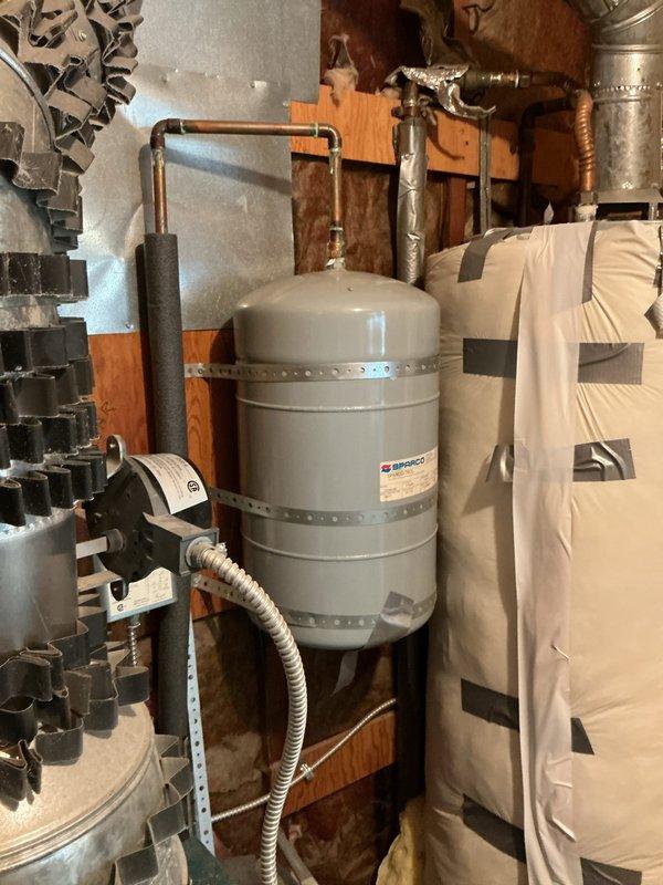 Completed comprehensive inspection and evaluation of 10+ year old boiler system located in utility room. Assessed condition of teal-colored boiler unit, associated piping infrastructure including copper lines with protective wrapping, red circulation pump assembly, yellow flexible gas line connections, and cylindrical expansion tank mounted on wall studs. Evaluated all mechanical components, ventilation systems, flexible conduits, and pressure vessel for replacement recommendation. Documented existing equipment configuration and provided estimate for complete system replacement based on age and condition of current heating plant.