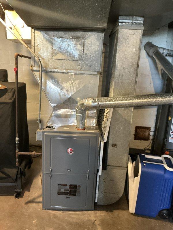 Completed full system assessment of existing HVAC equipment located in basement utility area of upstairs/downstairs duplex property. Inspected gray metal furnace unit with metallic exhaust pipe and insulation wrap, evaluated condition of copper supply lines with shutoff valve, and assessed ductwork distribution system. Documented current system configuration including PVC condensate drainage, electrical service panels with multiple breaker boxes, and overall equipment accessibility in common basement area. Provided comprehensive replacement quote for complete HVAC system upgrade based on current equipment age and homeowner's request for full system replacement options.