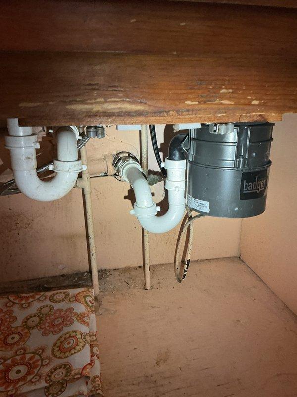 Responded to clogged washtub drain in basement utility area. Inspected drainage system and identified blockage preventing proper water flow from washtub. Cleared obstruction from drain line using appropriate tools and verified proper drainage restored. Examined plumbing configuration under kitchen sink area including P-traps, PVC drainage pipes, and garbage disposal unit to ensure no secondary blockages or issues affecting the washtub drainage system. Confirmed all drain lines flowing properly and washtub draining completely upon service completion.