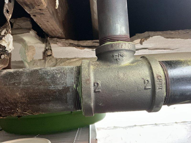 Conducted site inspection and assessment of damaged 3-inch stream line piping in basement area. Documented hole in corroded horizontal pipe section connected to T-joint fitting, with evidence of significant deterioration on galvanized and metal piping components. Photographed existing plumbing infrastructure showing mixed pipe materials, including PVC and insulated lines, with visible corrosion and wear throughout the system. Prepared documentation for estimate of necessary piping repairs and replacement work.