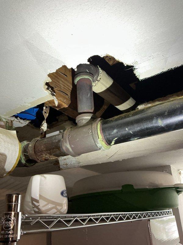 Conducted site inspection and assessment of damaged 3-inch stream line piping in basement area. Documented hole in corroded horizontal pipe section connected to T-joint fitting, with evidence of significant deterioration on galvanized and metal piping components. Photographed existing plumbing infrastructure showing mixed pipe materials, including PVC and insulated lines, with visible corrosion and wear throughout the system. Prepared documentation for estimate of necessary piping repairs and replacement work.