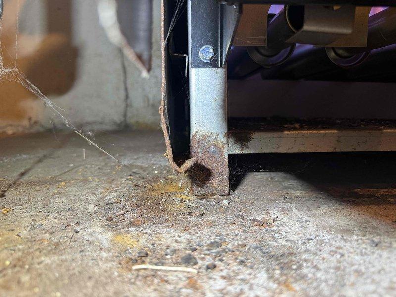 Completed comprehensive tune-up inspection on 10+ year old HVAC system located in basement, including full evaluation of furnace, humidifier, thermostat, and hot water tank components. Documented significant rust corrosion at base of equipment support structure where metal post contacts concrete floor, requiring attention to prevent structural integrity issues. Observed aged copper plumbing with visible oxidation, green patina formation, and corrosion on water lines and brass fittings throughout the system.