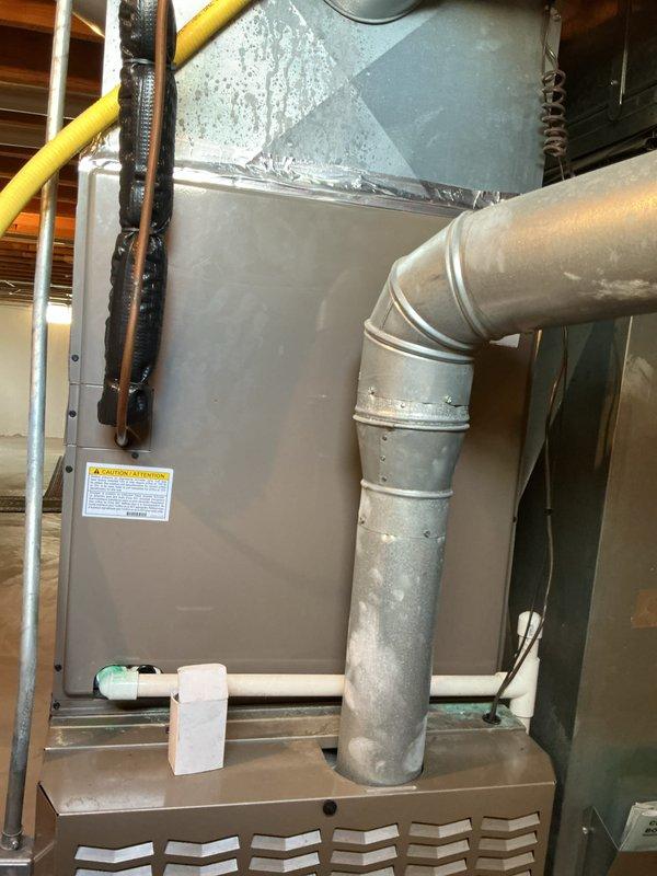 Conducted comprehensive HVAC estimate for replacement of 20+ year old furnace system located in basement. Evaluated existing beige furnace unit with associated ductwork, inspected humidifier operation, verified thermostat functionality, and assessed hot water tank condition. Documented current system configuration including air handler, metal ductwork with elbow joints, and gas line connections to provide accurate replacement recommendations for aging equipment.