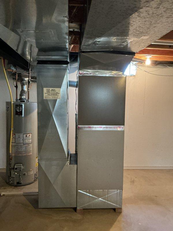 Conducted comprehensive HVAC estimate for replacement of 20+ year old furnace system located in basement. Evaluated existing beige furnace unit with associated ductwork, inspected humidifier operation, verified thermostat functionality, and assessed hot water tank condition. Documented current system configuration including air handler, metal ductwork with elbow joints, and gas line connections to provide accurate replacement recommendations for aging equipment.