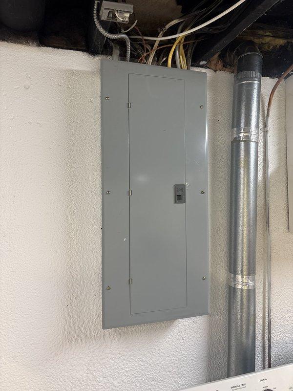 Completed comprehensive electrical panel inspection for city compliance on 20-year-old residential system. Performed thorough examination of main distribution panel containing approximately 20-24 circuit breakers arranged in dual columns, verified proper wire connections and color coding throughout, inspected all incoming conductors from overhead ceiling cavity, and documented panel condition with detailed photography. All breakers, wiring terminations, and panel enclosure found to be accessible and properly secured for municipal inspection approval.