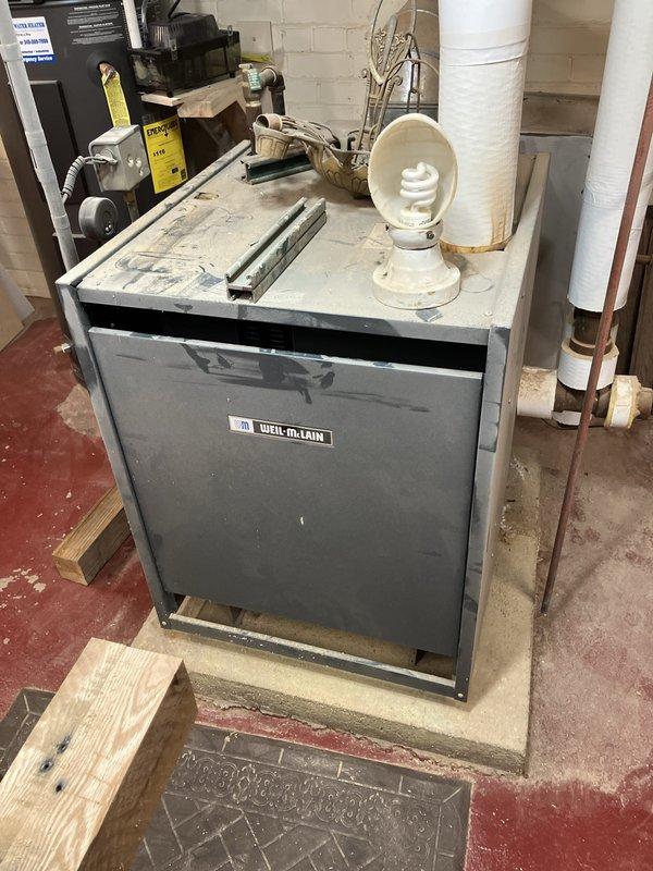 Conducted on-site assessment of 40-year-old Weil-McLain steam boiler system in basement. Identified cracked heat exchanger with active leak requiring immediate attention. Documented existing installation including associated piping, connections, and mechanical components. Photographed current boiler configuration, PVC venting system, copper supply lines, and shut-off valves for replacement planning purposes. Provided comprehensive estimate for complete boiler replacement due to failed heat exchanger beyond economical repair.