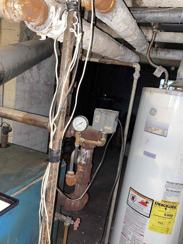 Conducted on-site evaluation of failed residential boiler system with hot water radiator distribution. Documented extensive corrosion throughout existing boiler unit, piping infrastructure, and expansion tank, along with evidence of water damage at base of equipment. Provided estimate for complete boiler replacement and installation to restore heating system functionality.