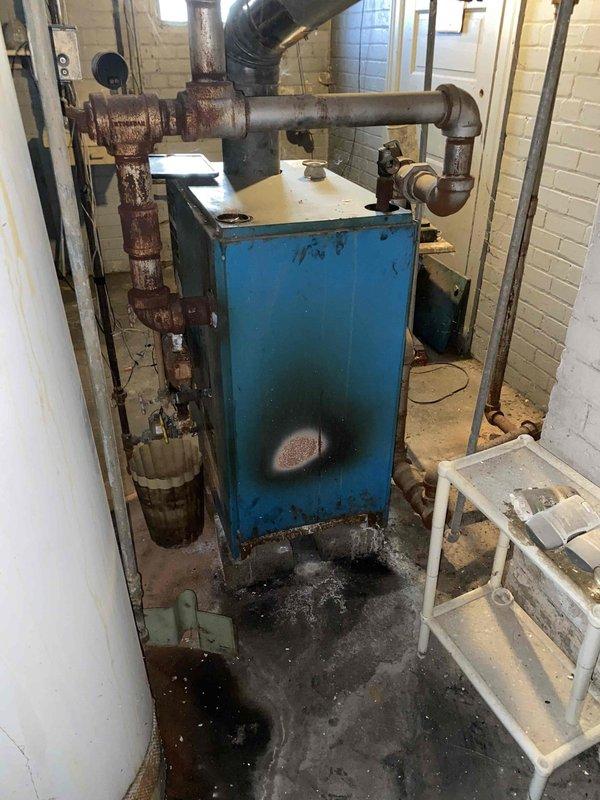 Conducted on-site evaluation of failed residential boiler system with hot water radiator distribution. Documented extensive corrosion throughout existing boiler unit, piping infrastructure, and expansion tank, along with evidence of water damage at base of equipment. Provided estimate for complete boiler replacement and installation to restore heating system functionality.
