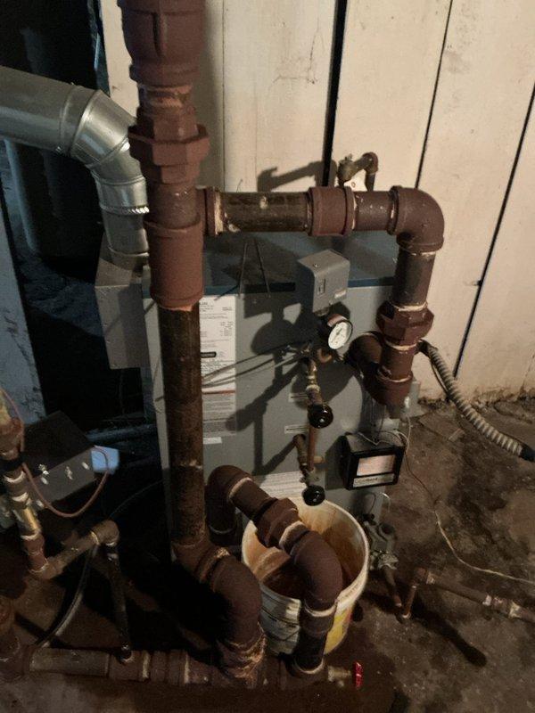 Completed pre-season tune-up on 6-year-old residential boiler system in basement prior to winter operation. Performed comprehensive inspection of heat exchanger, burner assembly, and ignition components. Cleaned and adjusted burner for optimal combustion efficiency. Tested and verified all safety controls including pressure relief valve, limit switches, and low water cutoff. Inspected expansion tank and pressure gauge for proper operation. Examined copper piping network and identified moderate oxidation on distribution lines, though system integrity remains sound. Verified proper venting configuration and checked for any blockages or deterioration. Tested circulator pump operation and lubricated as needed. Checked system pressure and topped off as necessary. Performed combustion analysis to ensure proper air-fuel mixture and safe operation. Verified thermostat operation and system response. All components functioning within manufacturer specifications. System ready for heating season o