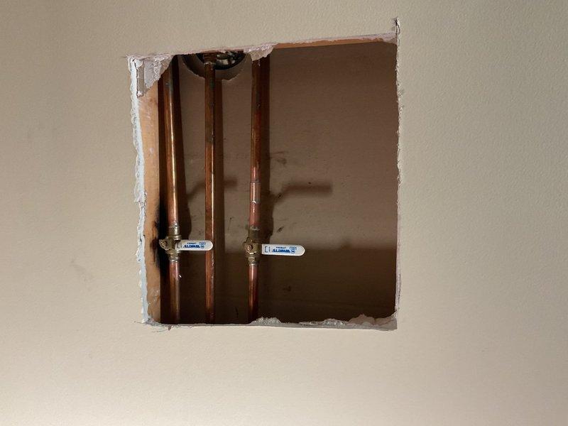 Installed two shut-off valves on the shower supply lines in the main second-floor bathroom. Cut access openings in the wall to expose the copper water supply pipes, installed isolation valves on each feed line to allow independent shut-off capability for future maintenance or repairs.