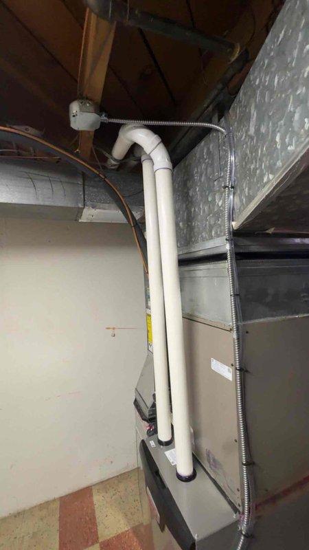 Completed installation of 70,000 BTU gas furnace in residential basement location. Installed new white PVC intake and exhaust venting system with proper vertical routing and secure fittings. Configured condensate drainage system with PVC piping and trap assembly to handle moisture removal. Reconnected all electrical connections using flexible metal conduit and verified proper grounding. Installed air handler unit with ductwork connections to existing system. Measured and verified return air configuration for optimal system performance. All components mounted securely to manufacturer specifications with appropriate clearances maintained. System tested and confirmed operational upon completion.