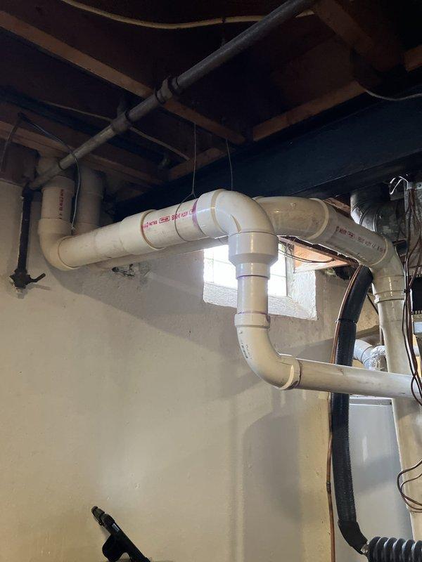 Conducted comprehensive full system estimate for complete HVAC replacement in residential basement installation. Evaluated existing Gibson furnace unit with associated electrical disconnect panels, gas line connections with shutoff valve, PVC condensate drainage system, and flexible return air ducting. Assessed current mechanical room configuration including electrical service panels, ventilation piping routing through floor joists, and utility connections. Documented equipment specifications, clearance requirements, and existing infrastructure conditions. Photographed installation area showing gas piping with blue-handled valve, white PVC drain lines with multiple elbows and fittings, corrugated flexible hoses, electrical wiring bundles, and concrete floor space. Reviewed ceiling joist layout and available routing options for new ductwork and venting systems. Measured clearances around existing equipment platform and evaluated structural framing for new system installation requirement