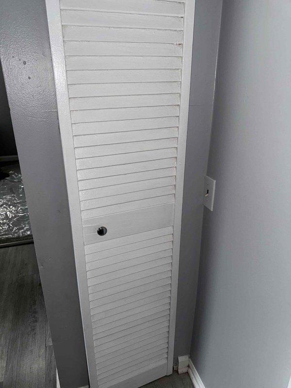 Responded to service call for furnace tripping breaker immediately upon startup with no operation. Unit located in kitchen closet, older model with unknown age. Upon arrival, accessed furnace behind louvered ventilation door and performed visual inspection of internal components. Observed blower motor assembly with accumulated dust and debris on motor housing and surrounding ductwork. Identified electrical short circuit condition causing immediate breaker trip. Inspected blower motor, capacitor, and wiring connections for signs of failure or damage. Determined blower motor had failed internally, creating direct short to ground. Advised customer of findings and recommended motor replacement to restore system operation safely.