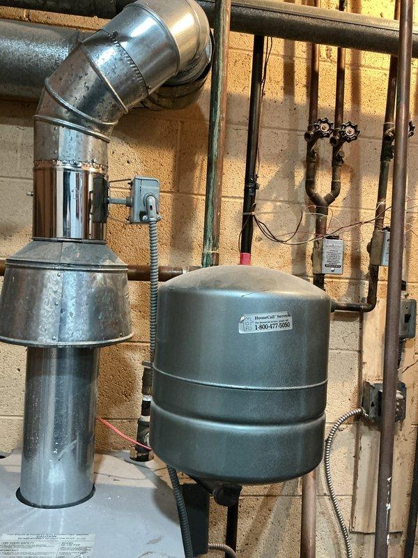 Responded to a service call for a hot water boiler located in the basement to investigate a potential valve issue and perform a tune-up. Upon inspection, observed significant corrosion and oxidation on the copper piping with greenish-blue patina and mineral deposits present, along with visible deterioration on heat exchanger components indicating extended service life and moisture exposure. Evaluated the expansion tank, venting system, gas line configuration, and associated plumbing connections to assess overall system condition and identify any immediate concerns requiring attention.