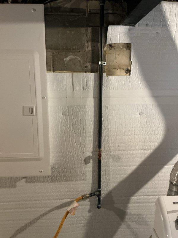 Completed gas line installation for dryer and rebuilt chimney stack in basement utility area. Installed new black steel gas piping with proper mounting brackets and flexible brass connector, ensuring secure connection and code-compliant installation. Performed structural work on stack system, including access port modifications and proper sealing of penetrations through wall surfaces.