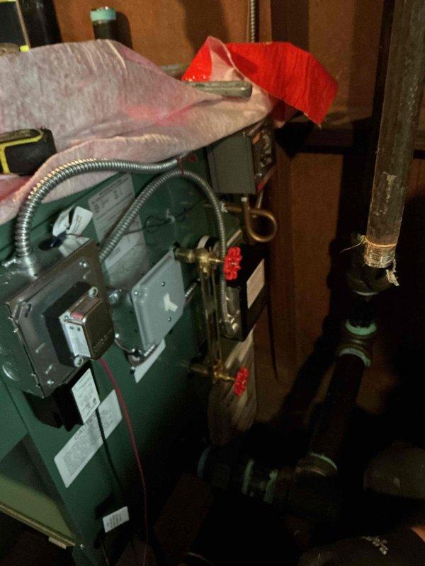 Completed full boiler installation in basement mechanical room, including new green heating unit with proper venting and piping connections. Installed expansion tank, connected copper supply and return lines with brass isolation valves and red-handled controls, and established all necessary ductwork connections to existing HVAC system. All components properly secured to wooden framing, system tested and operational, with permit requested for final inspection.