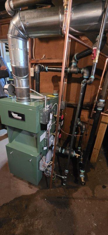 Completed full boiler installation in basement mechanical room, including new green heating unit with proper venting and piping connections. Installed expansion tank, connected copper supply and return lines with brass isolation valves and red-handled controls, and established all necessary ductwork connections to existing HVAC system. All components properly secured to wooden framing, system tested and operational, with permit requested for final inspection.
