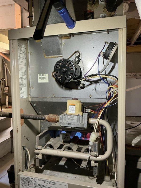 Completed comprehensive furnace maintenance on a 30-year-old gas furnace unit located in basement. Performed full system inspection with front panel removal to access internal components including blower motor, gas valve assembly, heat exchanger, and control wiring. Inspected all electrical connections, burner assembly, and condensate drainage system with white PVC piping. Verified blower motor operation and mounting integrity. Examined heat exchanger for signs of deterioration or cracking given the age of the unit. Checked gas valve, associated piping, and safety controls for proper operation. Measured supply air temperature at 72.1°F at ductwork to verify heating performance. Inspected flexible ductwork connections and verified proper airflow. Cleaned accessible components and removed dust accumulation from internal surfaces. All components functioning within normal parameters at time of service.