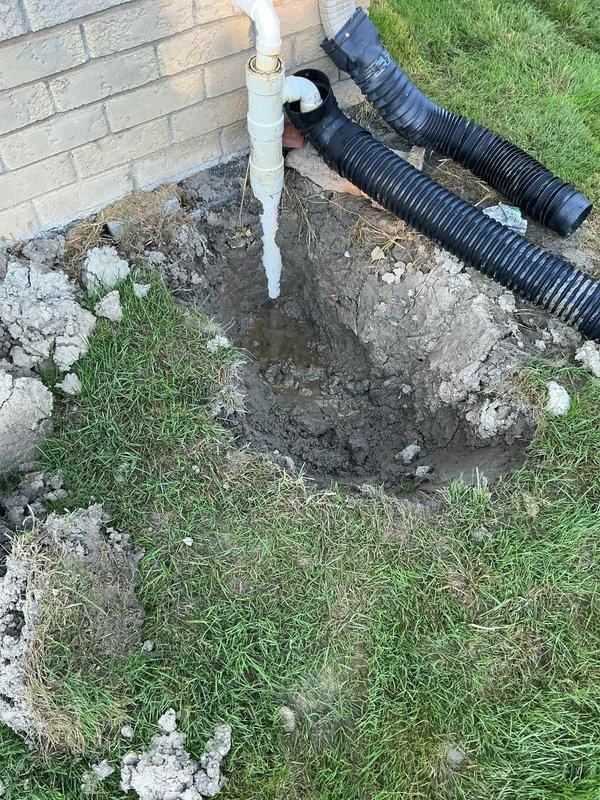 Responded to a sump pump discharge line issue where water was spitting out through the vent and causing exterior leakage. Upon inspection, confirmed the discharge line was clogged, preventing proper water flow from the basement sump pump system. Excavated and cleared the obstruction from the exterior drainage system, which included black corrugated perforated drainage pipes running from the foundation. Restored proper water flow through the discharge line and verified the sump pump was operating correctly with no further leakage at the vent or exterior discharge point.