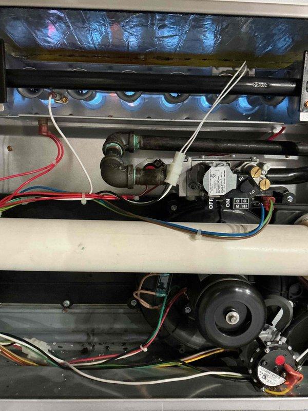 Completed comprehensive furnace inspection and tune-up on forced air heating system located in basement. System is less than 10 years old and operating within normal parameters. Performed visual inspection of all internal components including burner assembly, heat exchanger, gas valve, ignition system, and blower motor. All burner tubes showed proper flame characteristics with blue flame pattern indicating complete combustion. Verified gas connections and fittings for integrity; noted minor surface oxidation on some fittings which is typical for equipment age but does not affect operation. 

Inspected electrical components including control board, relays, and wiring connections. All connections secure with no signs of overheating or deterioration. Tested and verified proper operation of safety controls and limit switches. Blower motor assembly inspected and found in good working condition with normal operational sounds.

Conducted airflow measurements using manometer, recording static 