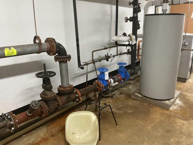 Responded to commercial backflow preventer failure in mechanical room. Upon inspection, identified two faulty backflow prevention assemblies exhibiting active leakage and one inoperable gate valve. The backflow devices showed significant corrosion on valve bodies, flanges, and internal components, compromising their ability to maintain proper check valve function and prevent reverse flow contamination. The non-turning valve displayed seized operation due to mineral buildup and deteriorated internal mechanisms. Documented existing plumbing configuration including corroded gate valves, pressure gauges, and interconnected piping systems. Photographed current conditions of both backflow assemblies and surrounding infrastructure to support repair recommendations and compliance requirements for commercial cross-connection control.