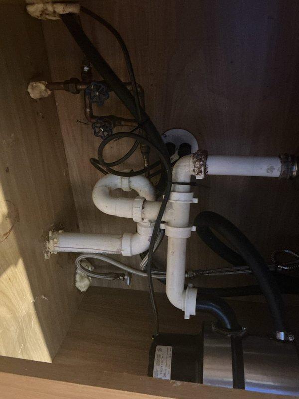 Performed preparatory plumbing work under kitchen sink in advance of dishwasher installation. Cleaned and serviced existing PVC drain assembly, including P-trap and associated fittings. Disconnected and removed old dishwasher unit, including water supply line and drain connections. Inspected copper supply lines and shutoff valves to ensure proper function for new appliance installation. Cleared cabinet space and verified all plumbing connections were secure and operational.