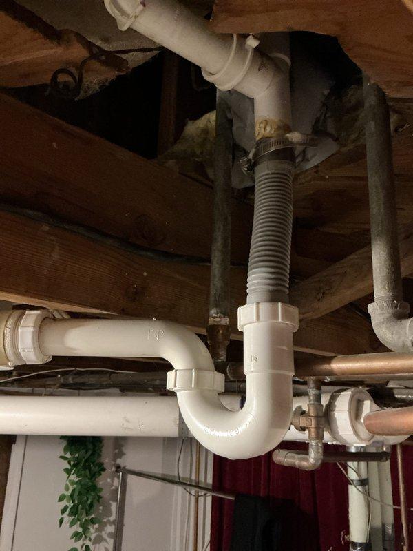 # Sump Pump Leak Repair

Responded to service call for reported sump pump leak in basement area. Upon arrival, conducted thorough inspection of existing sump pump system installed in circular black basin set into concrete floor. Examined submersible pump unit, discharge piping configuration, and all connection points for signs of water seepage.

Inspected multiple PVC discharge lines including white and beige pipes secured with metal hose clamps, noting age-related wear and discoloration on existing plumbing components. Traced all piping connections from pump basin through overhead plumbing infrastructure, including P-trap assembly and corrugated flexible discharge line. Evaluated pipe joints, coupling connections, and clamp integrity throughout the system.

Identified source of leak at connection point and performed necessary repairs to eliminate water seepage. Tested pump operation through multiple cycles to verify proper function and confirm leak resolution. Checked float switch mec
