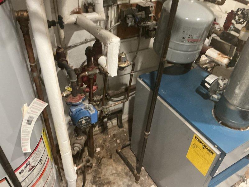 Responded to service call for 12-year-old steam boiler system with reported circulating pump failure and damaged radiator requiring replacement. Upon arrival, conducted comprehensive inspection of boiler unit located in closet, evaluating all mechanical components, piping connections, and circulation system. Assessed condition of existing circulator pump and verified operational status of heating distribution system. Performed thorough examination of radiator network to identify failed unit and determine extent of damage. Inspected all pipe connections, valves, and fittings throughout the system, noting areas of corrosion on copper piping and aging mechanical components. Evaluated boiler controls, expansion tank mounting, and associated plumbing infrastructure to ensure system integrity. Documented current system conditions including visible oxidation on metal components and wear patterns consistent with equipment age. Provided technical assessment and recommendations for circulator pu