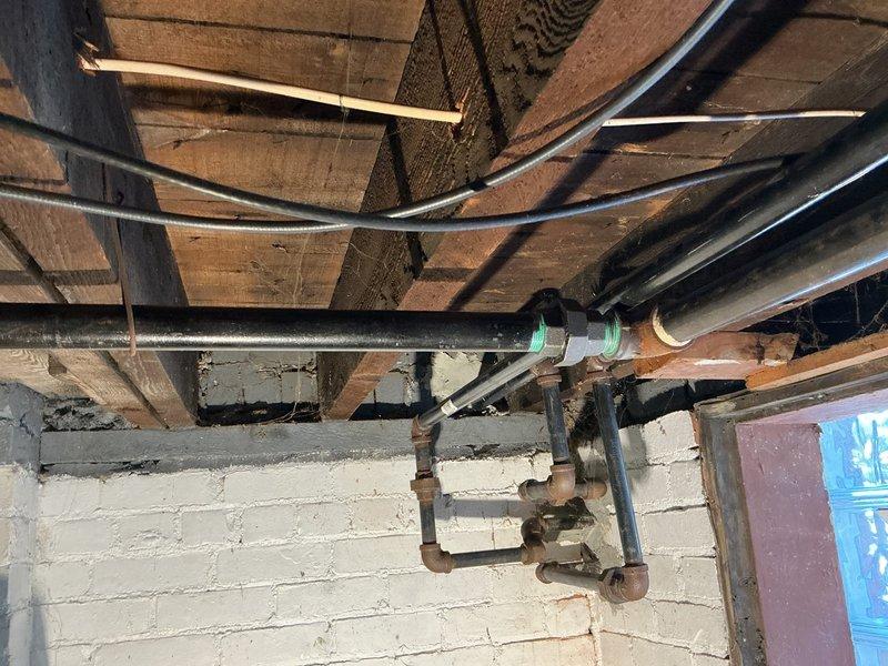 Completed gas line repairs in commercial basement utility area. Addressed aging copper pipe infrastructure showing oxidation and installed new black gas line routing along exposed floor joists with proper securing methods and code-compliant fittings. Ensured all connections were properly supported and secured to structural elements for safety and longevity of the installation.