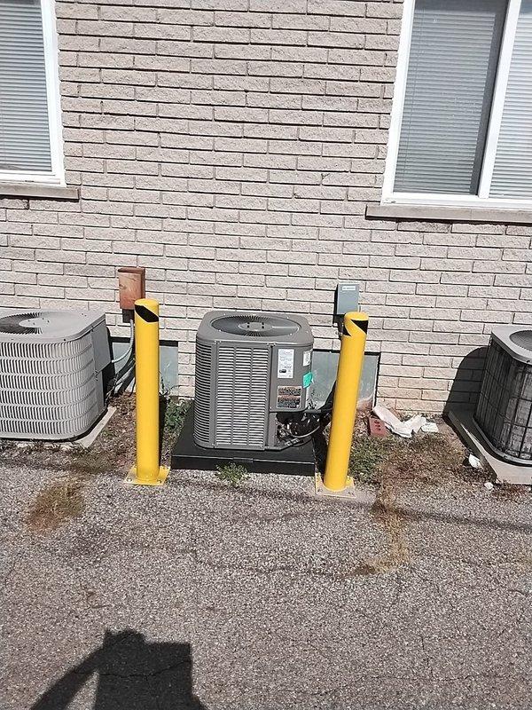 Installed yellow safety bollards around exterior HVAC units to comply with mechanical code violation identified during inspection. Three condensing units were protected with properly anchored bollards mounted on concrete pads with base plates and bolts, creating physical barriers against potential vehicular damage. Installation meets required safety standards and resolves the outstanding code compliance issue.