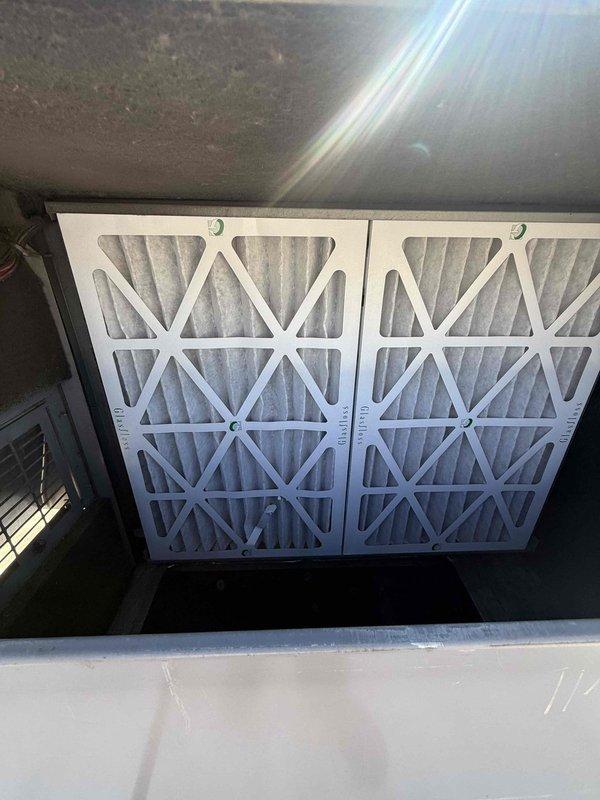 Performed scheduled commercial HVAC maintenance agreement service on two rooftop package units. Accessed RTUs using ladder to complete inspection and filter service. Inspected both rooftop units for proper operation, checked electrical connections and conduit integrity, and verified mounting brackets were secure. Replaced air filters in return air compartment with new pleated filters to maintain proper airflow and system efficiency. Noted existing roof membrane staining around unit base. Both RTU systems operational upon completion of maintenance visit.