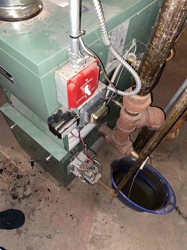 Responded to no heat complaint on 10-year-old boiler system located in basement. Upon inspection, found extensive corrosion and oxidation on copper piping throughout the heating system, with visible deterioration on vertical pipe runs, joints, and fittings. Noted active leak requiring bucket placement for water collection, with floor staining indicating ongoing moisture issues. Circulator pump, gas valve assembly, and associated piping connections showed significant age-related wear. Due to the extent of corrosion, compromised piping integrity, and safety concerns with the aging system components, provided comprehensive estimate for boiler replacement and associated piping upgrades to restore reliable heating operation.
