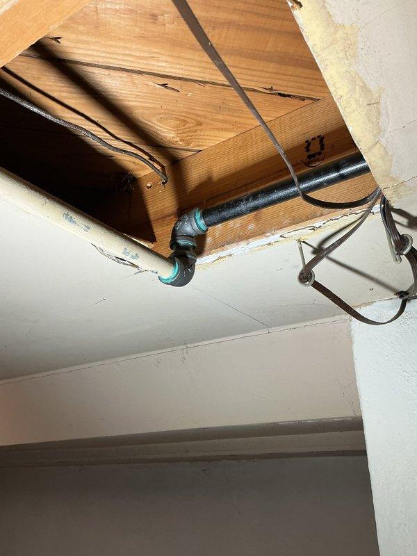 Completed gas line repairs in ceiling space as specified in estimate. Replaced deteriorated black iron pipe sections and installed new flexible couplings to ensure secure, leak-free connections. Secured all piping with proper metal straps and hangers attached to structural beams, bringing the system up to code compliance.