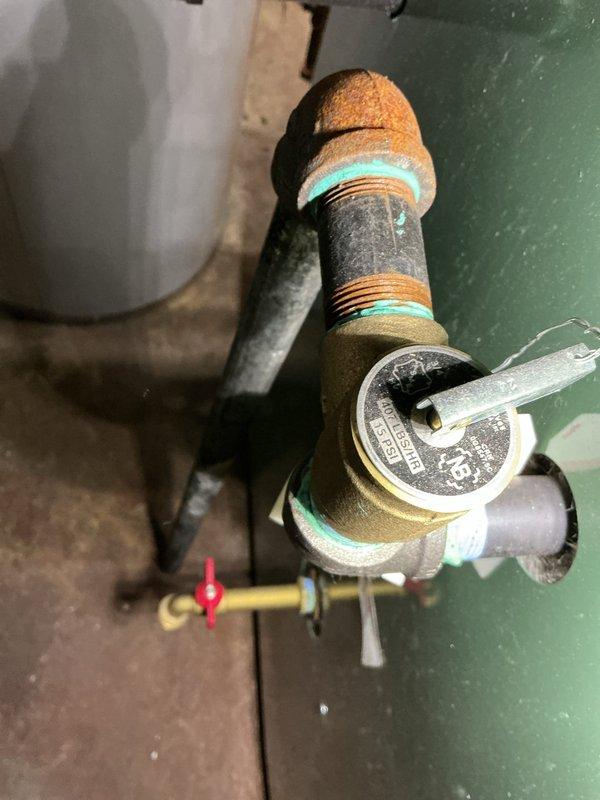 Completed comprehensive Gold Boiler Inspection on a 10+ year old steam boiler system located in basement. Performed thorough visual examination of all boiler components, including pressure gauge, gas manifold assembly, burner compartment, and associated piping systems. Inspected pressure regulator valve with circular gauge, isolation valves, and gas supply connections. Examined electrical wiring connections including ground wire and control wiring within burner compartment. Assessed pilot burner assembly and brass orifices on gas manifold. Evaluated condition of piping showing age-appropriate corrosion and surface weathering on steam lines and fittings. Verified proper insulation on overhead piping secured with retention bands. Documented condition of all components through photographic records. Unit confirmed operational at time of inspection with all safety controls functioning as designed.