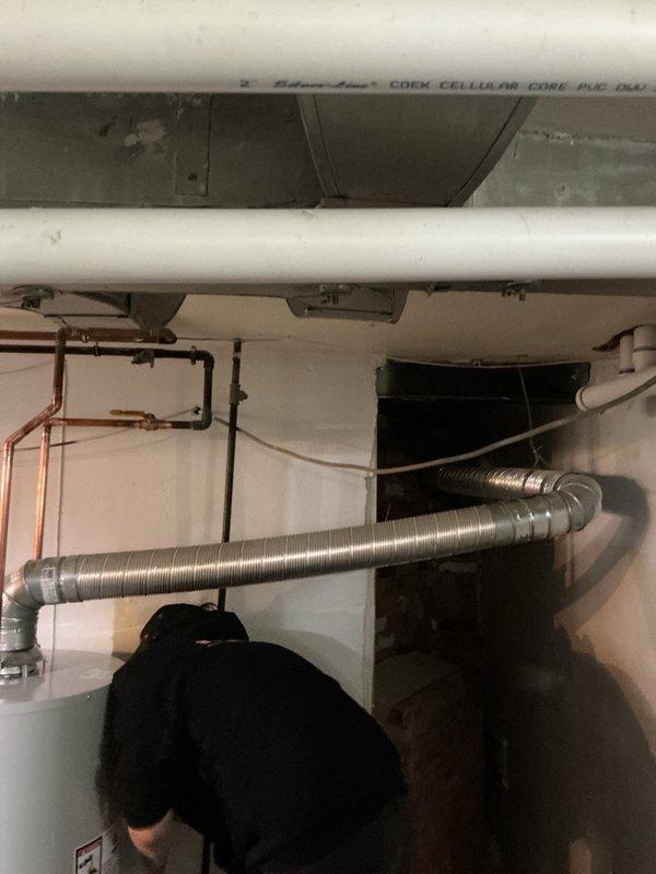 Completed installation of replacement tanked water heater in basement utility area with extended venting system. Due to the exceptionally long venting run required for this installation, additional venting materials were utilized to properly exhaust combustion gases from the unit. The installation included connecting flexible metallic ductwork with rigid metal elbows to accommodate the extended horizontal run across the ceiling space, ensuring proper draft and code compliance. All water supply connections were completed using existing copper piping infrastructure, and the unit was reconnected to the distribution system. The water heater was positioned and secured in accordance with manufacturer specifications and local plumbing codes. Final installation includes fully operational venting system with appropriate pitch and support, restored water service, and verified proper operation of all mechanical components.
