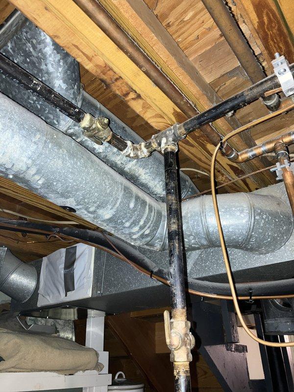 Completed comprehensive furnace inspection and evaluation on 16-year-old heating system located in basement. Assessed existing HVAC infrastructure including ductwork, venting components, and associated mechanical systems to determine replacement requirements. Documented current system configuration with detailed photographic analysis of exposed ductwork, gas piping connections, condensate drainage, and structural mounting points to develop accurate replacement specifications for single-unit residential forced air heating system.