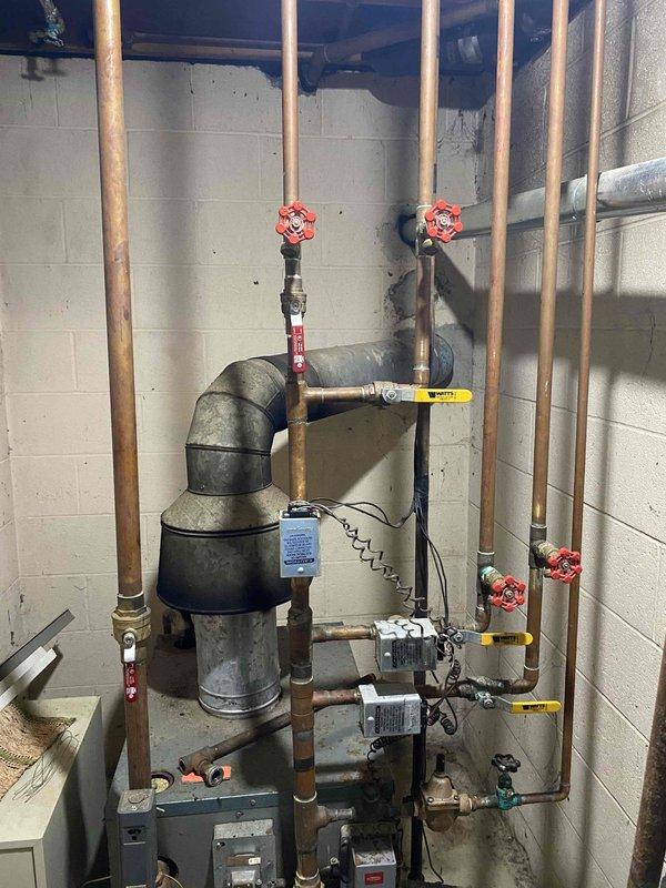 Conducted free estimate visit for replacement of 40-year-old boiler system located in basement. Documented existing equipment and plumbing configuration with photographs showing aged copper piping, multiple shut-off valves, heat exchanger components, and deteriorated concrete floor conditions around plumbing fixtures. Assessed current mechanical room layout including exposed framing, pipe runs, and existing connection points. Provided comprehensive replacement estimate for new boiler system installation.