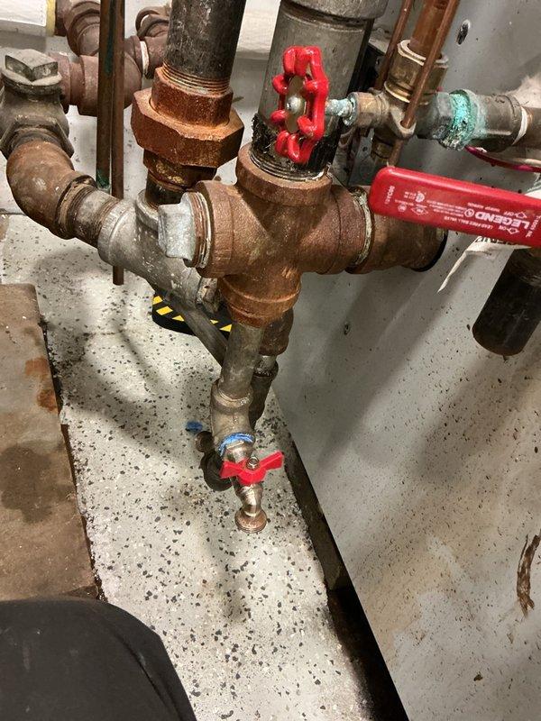Completed Gold-level maintenance inspection on residential steam boiler system. Performed comprehensive visual examination of boiler components, associated piping, valves, and pressure controls. Inspected water heater, circulation system, pressure vessel, and all interconnected mechanical equipment in basement mechanical room. Noted visible corrosion and oxidation on multiple pipe sections and threaded fittings throughout the system, particularly on horizontal runs and valve connections. Documented condition of red-handled gate valves, pressure gauge, control box, and copper piping. System operational at time of inspection; photographed equipment conditions for maintenance records.