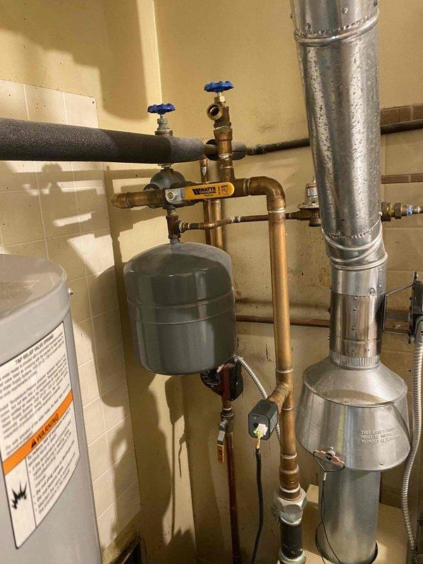 Provided estimate for replacement of 20-year-old hot water boiler system currently located in first floor utility room. Existing unit remains operational but has reached end of expected service life. Assessment included evaluation of current copper piping configuration, circulator pump, expansion tank, zone valves, and integration with existing domestic water heater and HVAC ductwork system to determine optimal replacement specifications and installation requirements.