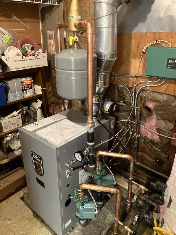 Completed full boiler installation in basement utility area, including mounting and connection of new heating unit with integrated expansion tank and copper piping distribution system. Installed two zone circulator pumps at base of unit for hydronic heating control, along with two thermostats and system controller with proper wiring to green control panel. Established all mechanical and electrical connections per code requirements, utilizing braided flex connectors and rigid copper piping with professional fittings throughout the system. Secured mechanical and electrical permits prior to installation and reconnected all heating zones to ensure proper system operation and zoning capability.