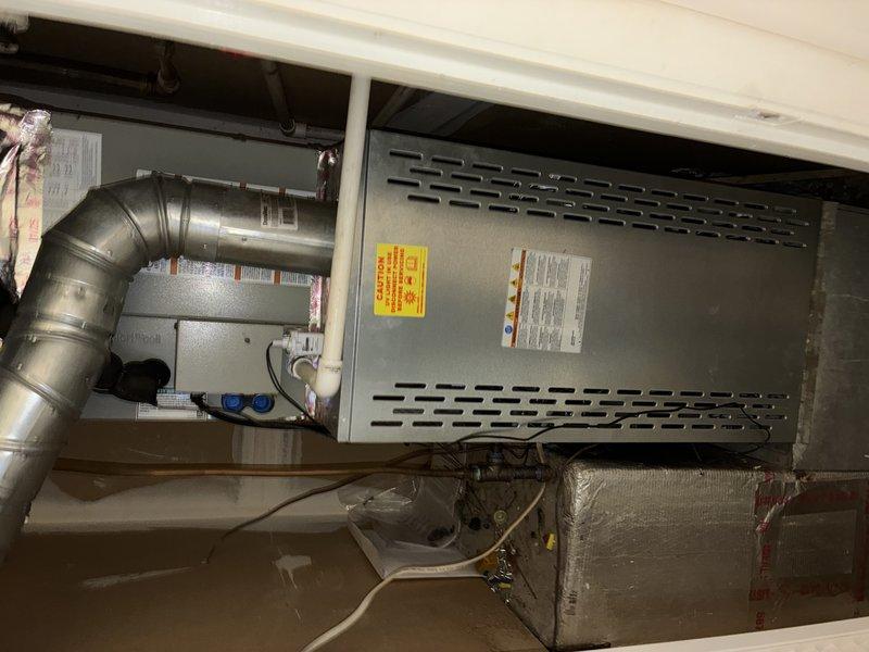 Completed first Protection Plan Preventive maintenance visit on residential HVAC system consisting of one heating unit and one air handler with UV light system under 12-month warranty. Performed comprehensive inspection of furnace and air handler assembly located in utility closet. Removed access panels and inspected all internal components including blower motor assembly, gas valve connections, ignition system, and control board. Verified proper operation of circuit board with LED indicator functioning correctly. Inspected all wire harnesses and electrical connections throughout unit for secure termination and proper routing. Examined ductwork connections including curved metallic elbow and insulated supply ducts with reflective foil backing. Confirmed all ventilation pathways clear and unobstructed. Verified UV light system present and installed in accordance with manufacturer specifications. Checked all safety labels and warning placards properly affixed to equipment. Photographed e