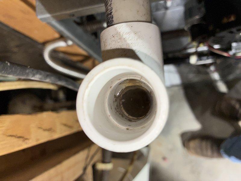 Responded to service call for air conditioning unit short cycling and failing to maintain temperature. Upon arrival, inspected outdoor condensing unit and found system experiencing frequent on-off cycling preventing adequate cooling. Examined condenser unit positioned on concrete pad against building exterior, noting operational fan assembly and intact cabinet with proper ventilation louvers. Investigated indoor components including condensate drainage system, observing PVC drain line with visible residue buildup and discoloration inside piping. Documented equipment conditions through photographs for service records. System requires further diagnostic testing to identify root cause of short cycling issue, which may include refrigerant charge verification, electrical component testing, thermostat calibration check, and potential condensate drain line cleaning to restore proper operation.