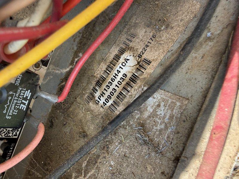 Completed drive-by inspection of residential HVAC system. Documented outdoor condensing unit condition, noting significant accumulation of dirt and debris on protective mesh screening and filter surfaces. Photographed unit identification barcode label (5P17390B11TCR) and observed dust buildup on internal metal components and electrical connections including visible red, yellow, and pink wiring harnesses.