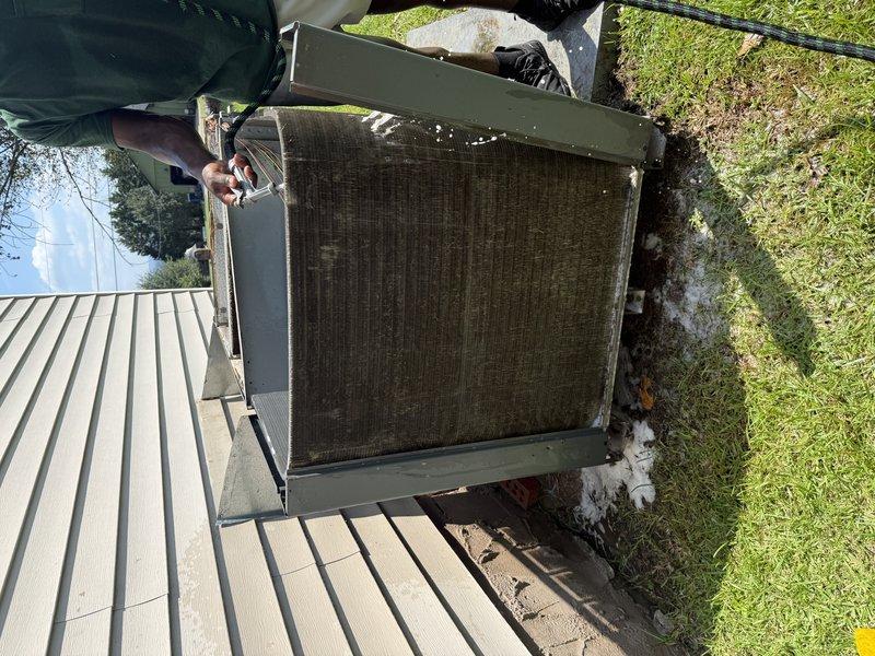Completed drive-by inspection of residential HVAC system. Documented outdoor condensing unit condition, noting significant accumulation of dirt and debris on protective mesh screening and filter surfaces. Photographed unit identification barcode label (5P17390B11TCR) and observed dust buildup on internal metal components and electrical connections including visible red, yellow, and pink wiring harnesses.