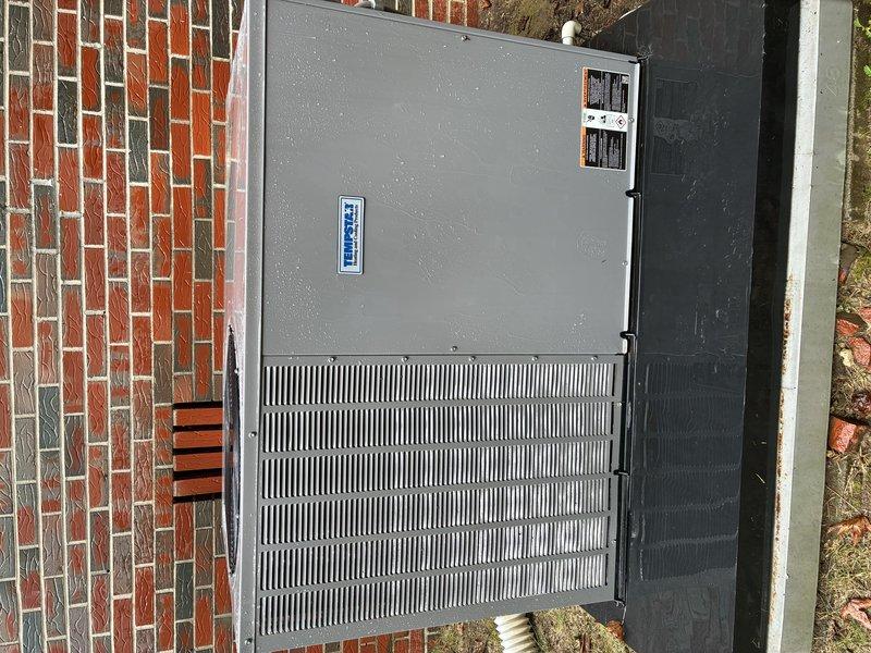 Completed Protection Visit on recently installed 12 SEER package unit with UV light system. Inspected outdoor HVAC unit mounted against brick wall, verified proper installation and operational status. Unit exterior showing no signs of damage or deterioration, all panels and grilles secure and intact. Manufacturer labels and information plates properly affixed and visible. Equipment positioned on stable concrete pad with adequate clearance for airflow and service access. Documented installation with photographs for service records.