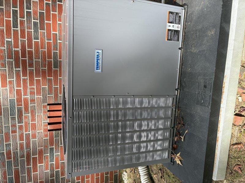 Completed Protection Visit on recently installed 12 SEER package unit with UV light system. Inspected outdoor HVAC unit mounted against brick wall, verified proper installation and operational status. Unit exterior showing no signs of damage or deterioration, all panels and grilles secure and intact. Manufacturer labels and information plates properly affixed and visible. Equipment positioned on stable concrete pad with adequate clearance for airflow and service access. Documented installation with photographs for service records.