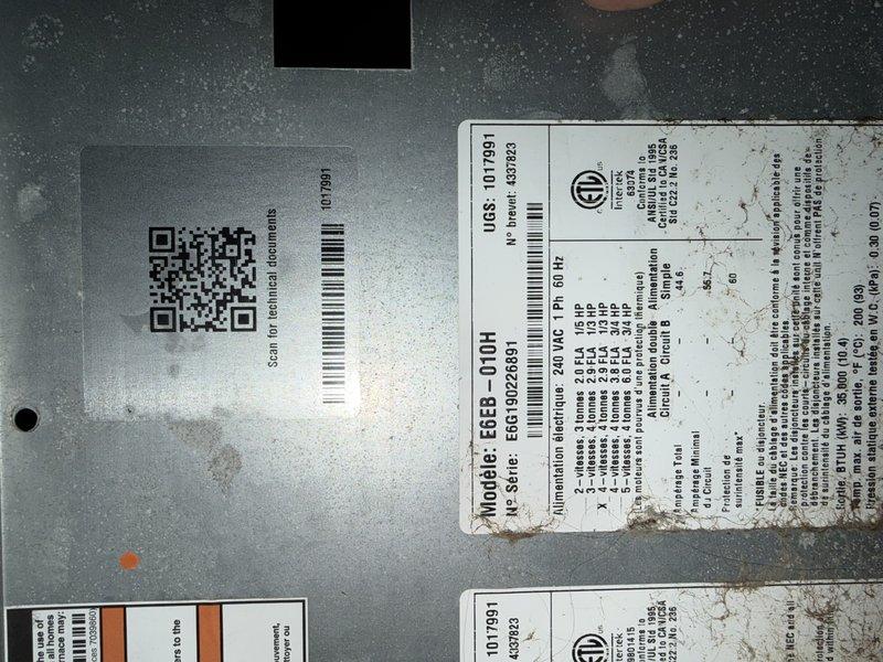 Completed drive-by inspection of HVAC unit and documented equipment condition through photographic assessment. Visual examination revealed unit identification labels, QR code, and manufacturer specifications on exterior casing, along with internal blower motor assembly showing significant dust accumulation on motor housing and surrounding components. Observed multiple electrical connections, copper refrigerant line, and finned heat sink component, all exhibiting operational wear and debris buildup consistent with equipment requiring maintenance attention.